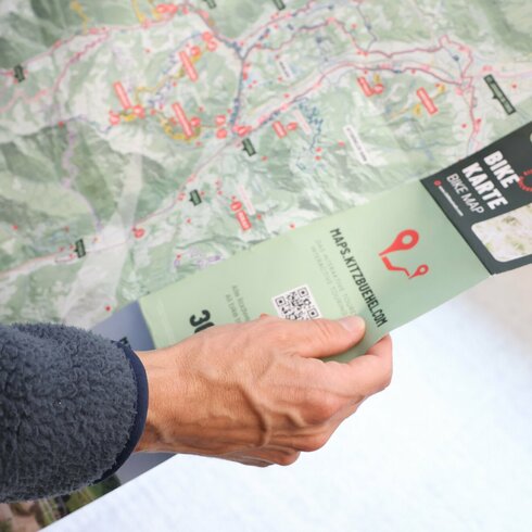 Ein weißer Flurbereich mit einer offenen Garderobe, Kissen und einem kleinen schwarzen Schild