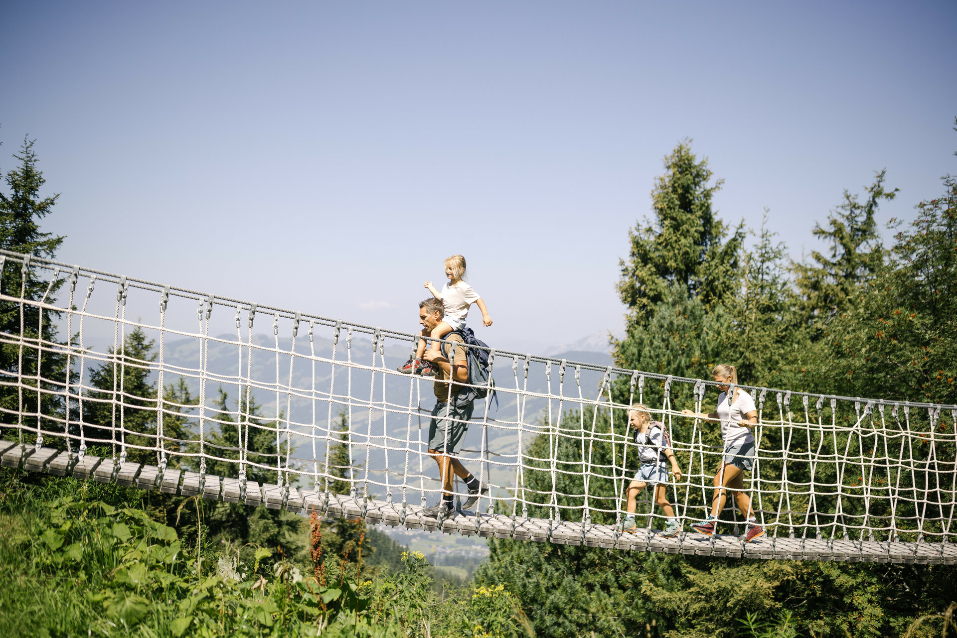 Familie geht über Seilbrücke
