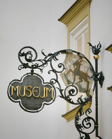 Ein weißer Flurbereich mit einer offenen Garderobe, Kissen und einem kleinen schwarzen Schild