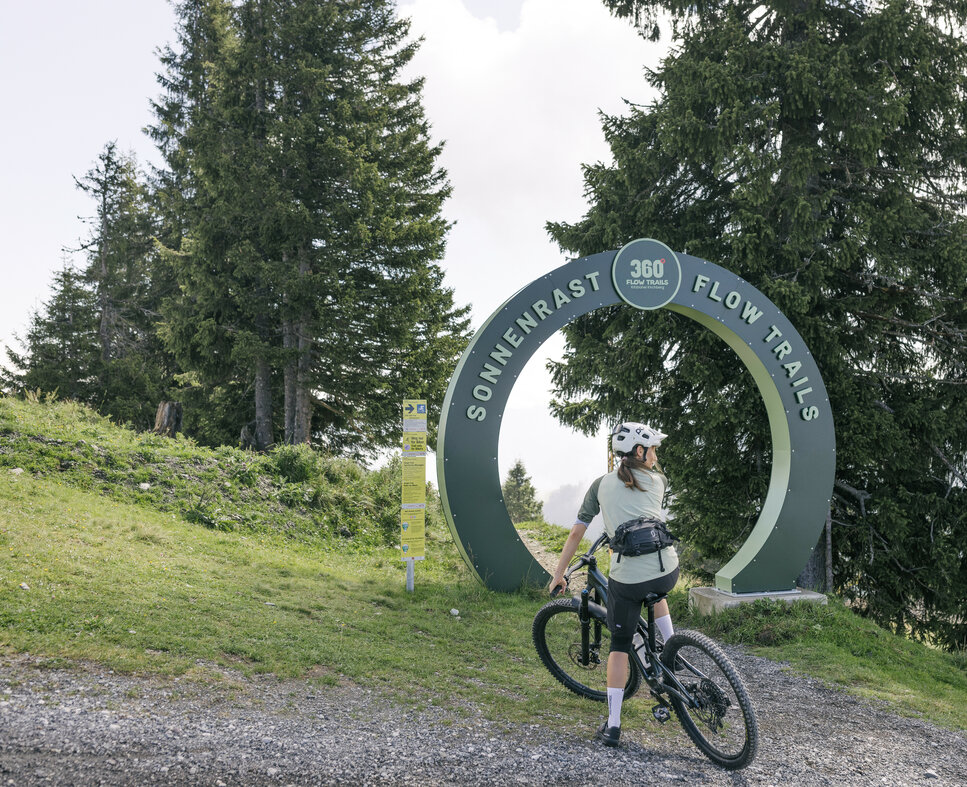 Ein weißer Flurbereich mit einer offenen Garderobe, Kissen und einem kleinen schwarzen Schild