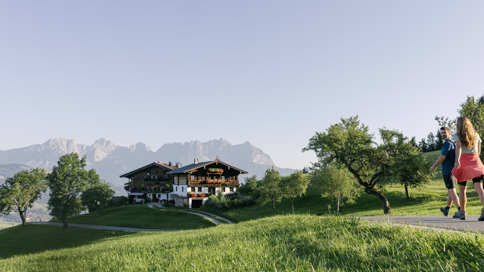 Menschen, die durch eine Wiese in den Bergen spazieren