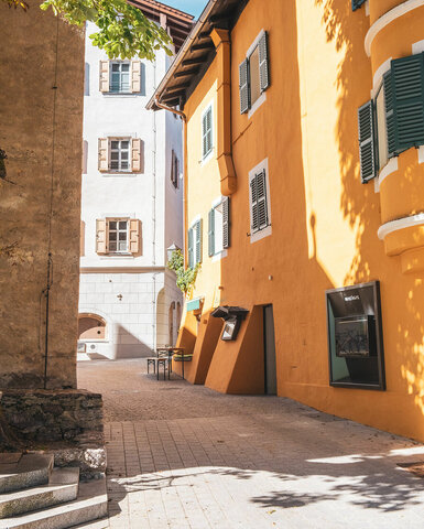 Ein weißer Flurbereich mit einer offenen Garderobe, Kissen und einem kleinen schwarzen Schild