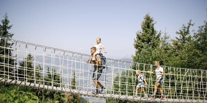 Familie geht über Seilbrücke