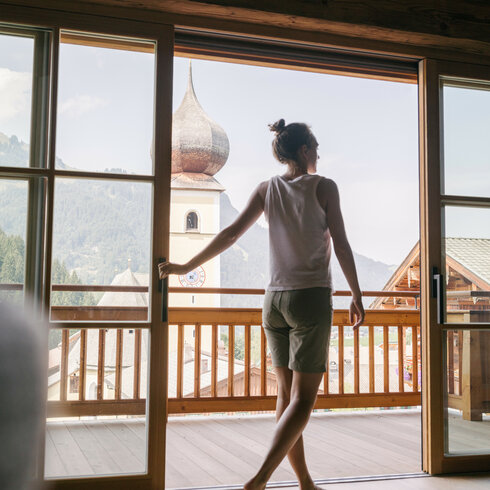 Ein weißer Flurbereich mit einer offenen Garderobe, Kissen und einem kleinen schwarzen Schild