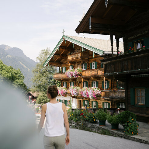 Ein weißer Flurbereich mit einer offenen Garderobe, Kissen und einem kleinen schwarzen Schild
