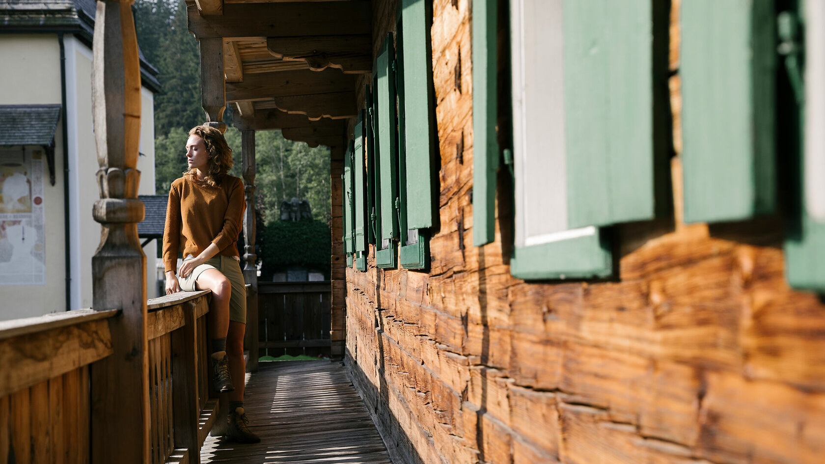 Lifestyle Erholung Kitzbuehel Sommer Balkon (c) Kitzbuehel Tourismus (11) Ein weißer Flurbereich mit einer offenen Garderobe, Kissen und einem kleinen schwarzen Schild