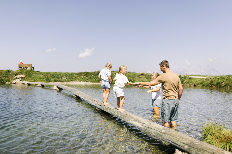 Familie, die über einen Holzstamm läuft.