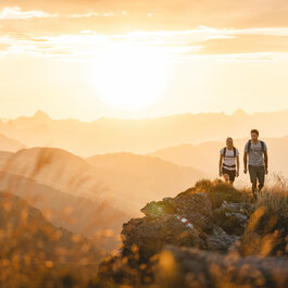 Zwei Menschen wandern bei Sonnenaufgang