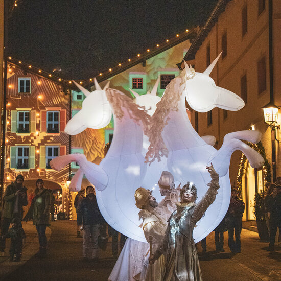 Ein weißer Flurbereich mit einer offenen Garderobe, Kissen und einem kleinen schwarzen Schild